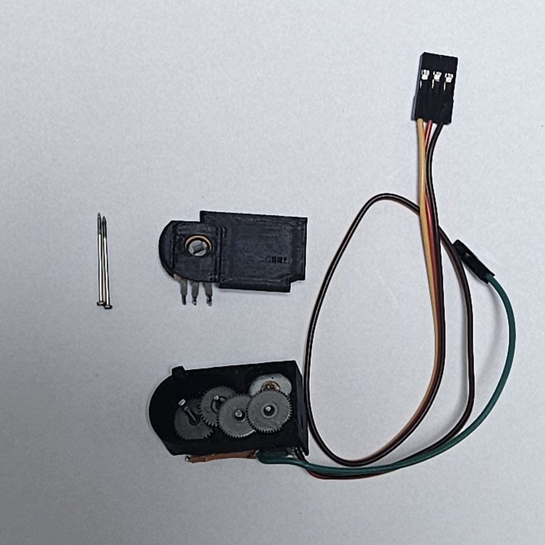 The same servo parts rearranged into a finger-shaped printed frame